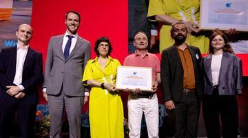 A row of people, two holding a framed award certificate