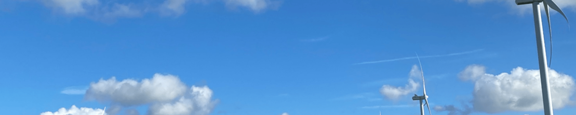 Blue sky with some cloud and windmills in foreground