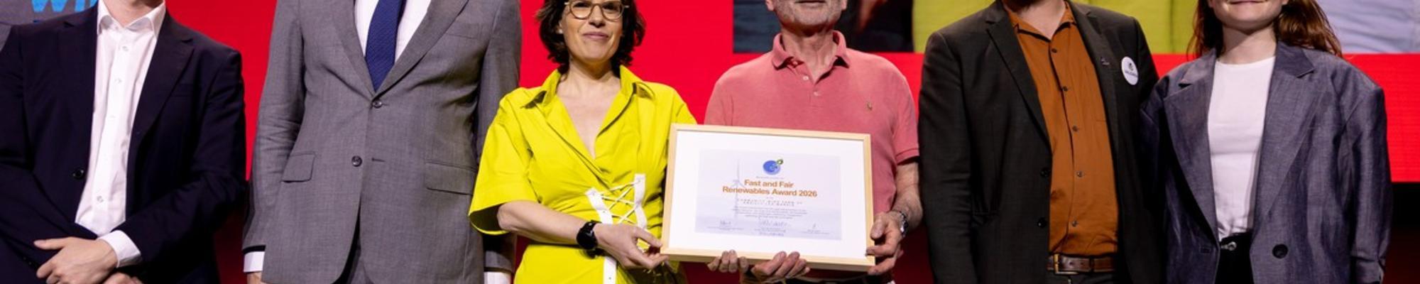 A row of people, two holding a framed award certificate